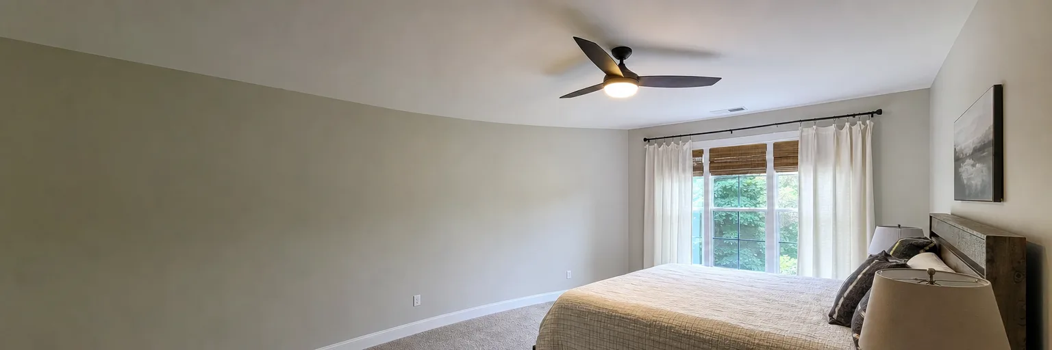 Three-blade ceiling fan and light fitted in a bedroom with a curtained window
